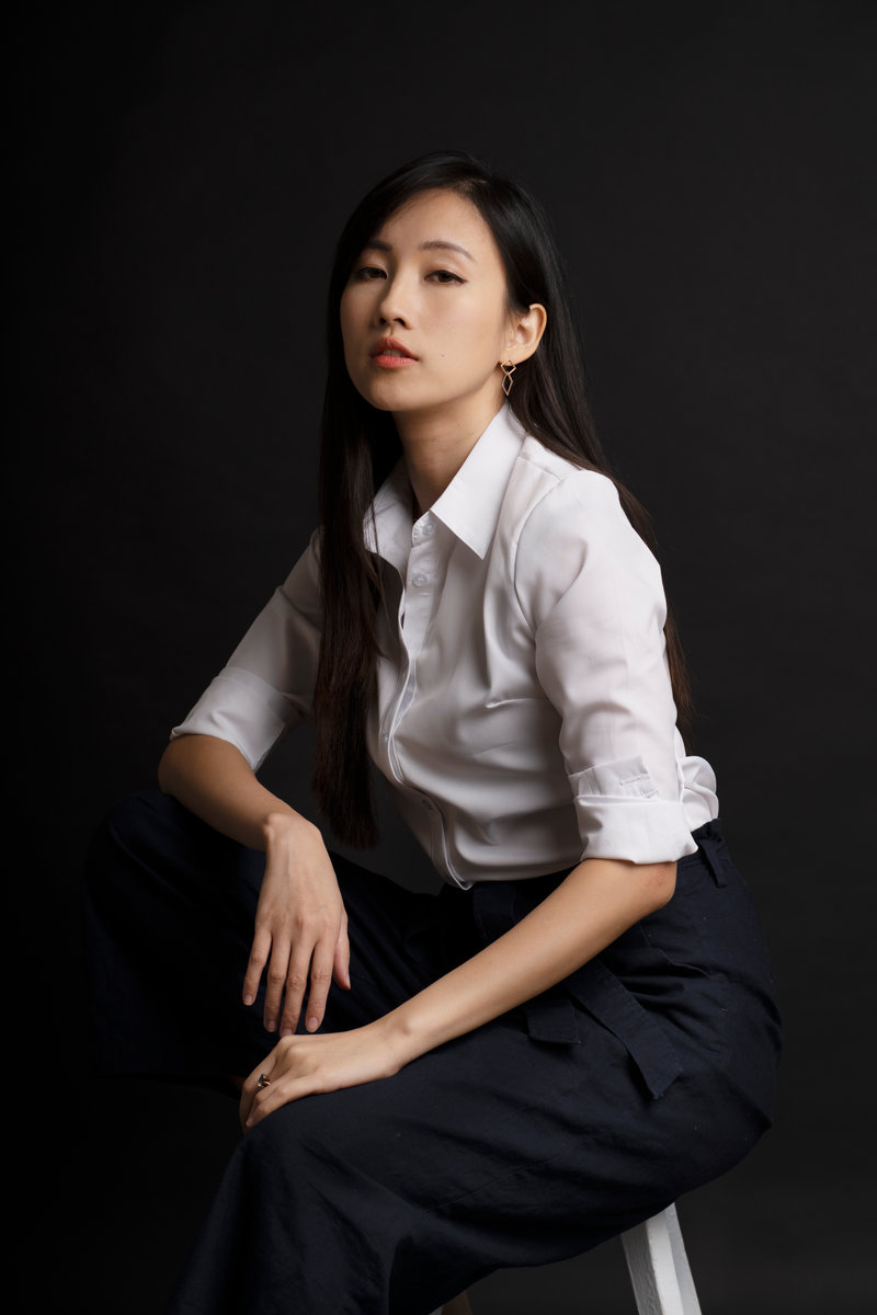 Studio portrait of a seated woman in a white blouse and dark trousers