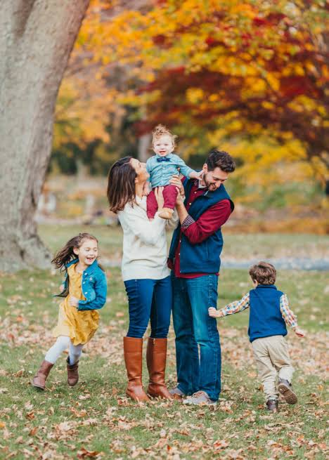 Parents and three children playing among autumn trees.